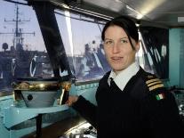 A photograph of a female naval officer at the helm