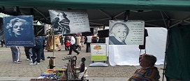 Some well-known figures (Marilyn Monroe, Oscar Wilde and Albert Einstein) gaze out on a campus filled with graduates (image depicts a stall owned by Phil Murphy, selling arts and crafts items, the bulk of which are Fairtrade products). 