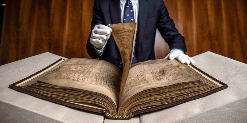 A picture of someone turning the page on the Book of Lismore