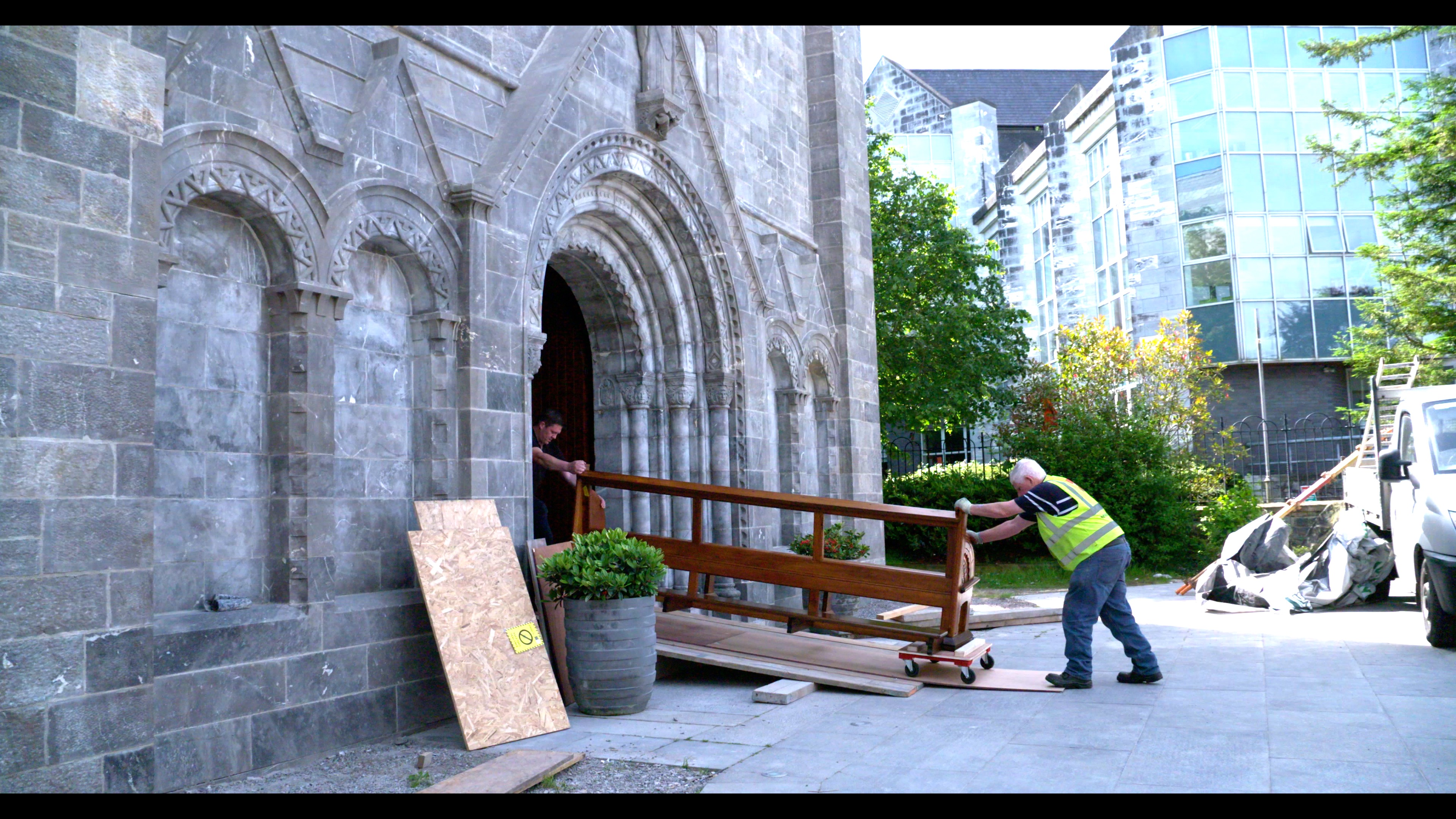 Two men bringing a pew into a church