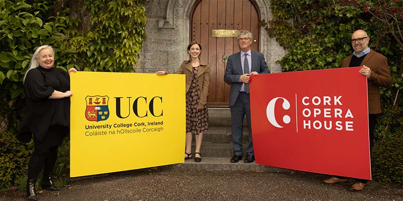 Two women and two men outside the UCC President's door holding signs that read UCC and Cork Opera House