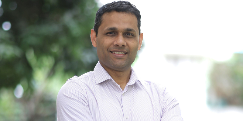 A profile photo of Dr Gaurav Rajauria, who is outside and wearing a white shirt, open at the collar.