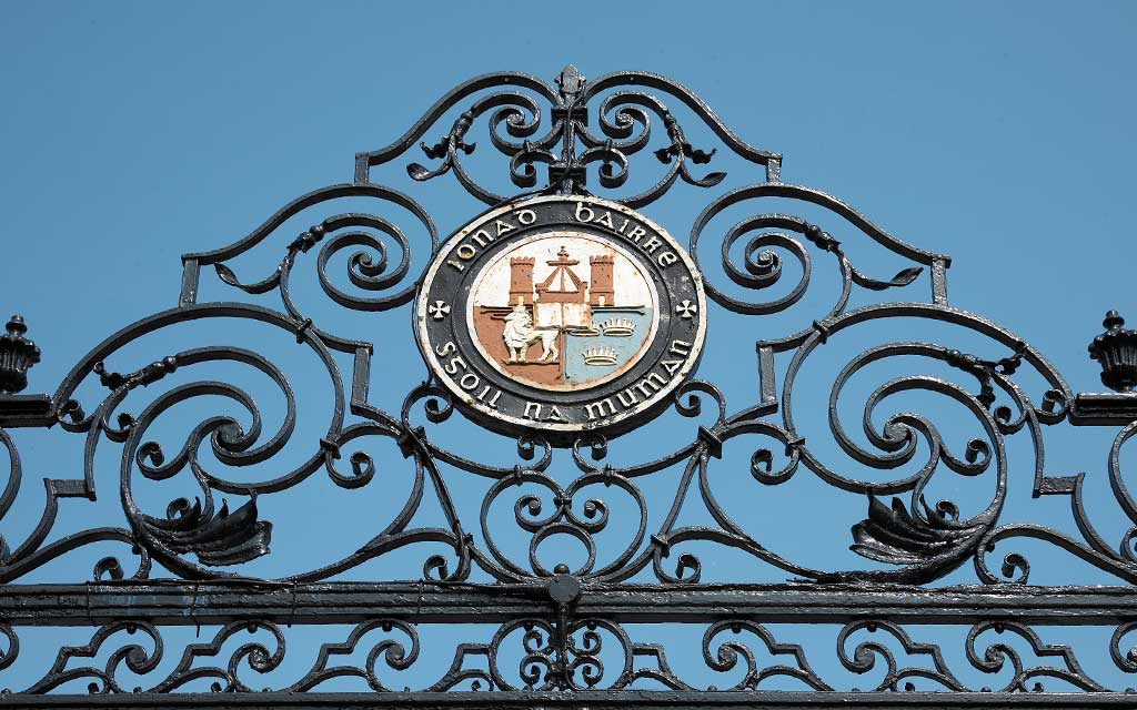 The UCC crest above the ceremonial entrance set against a clear sky
