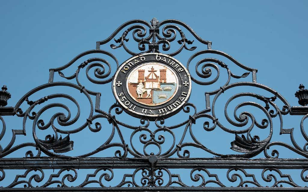 The UCC crest above the ceremonial entrance set against a clear sky
