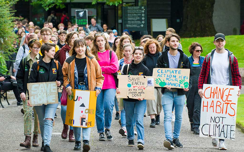 UCC community members bearing placards and signs protest for action on climate change and for a sustainable future