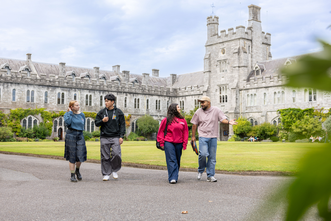 A group of students walking by the main Quadrangle building at UCC