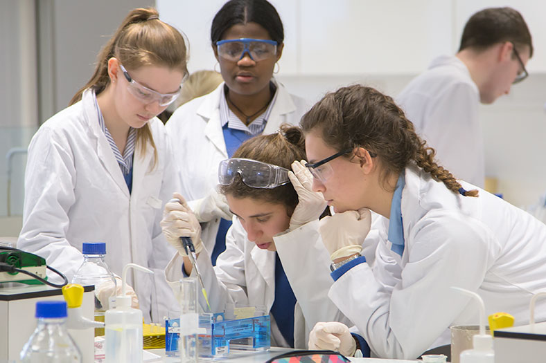 A group of secondary school students from Christ King Secondary School concentrate on loading a gel