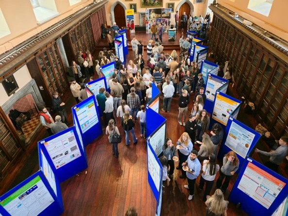 An overhead shot of an ornate hall with people and poster boards.