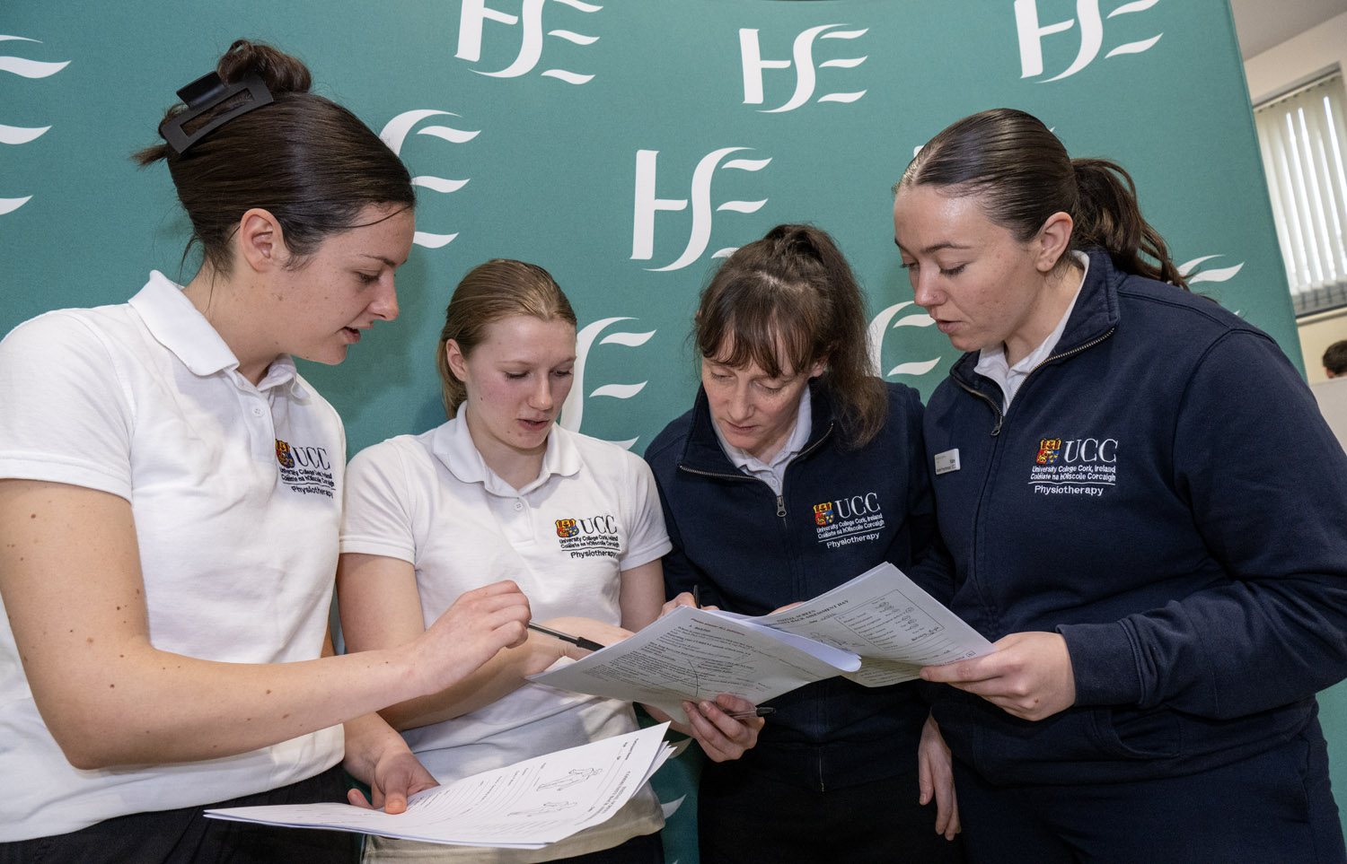 4 students standing together infront of a HSE banner looking at paperwork 4 students standing together infront of a HSE banner looking at paperwork