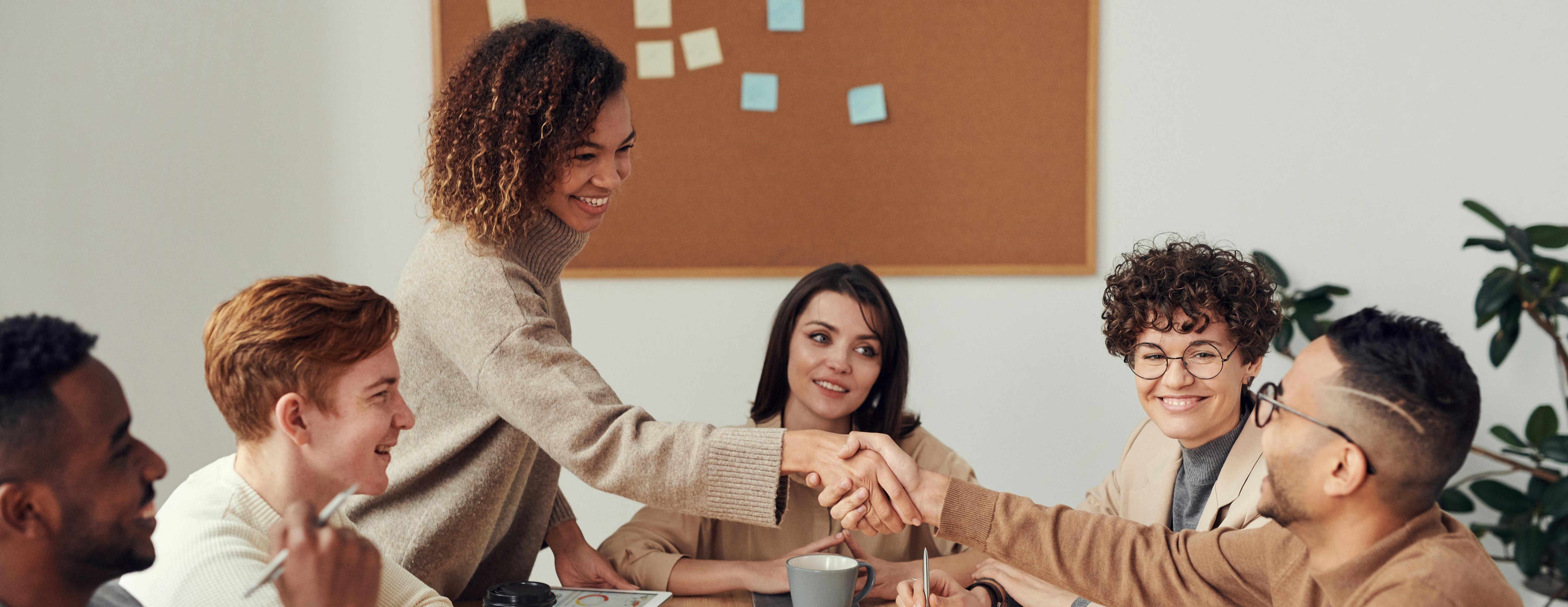 Group of people working together at a table with two people shaking hands