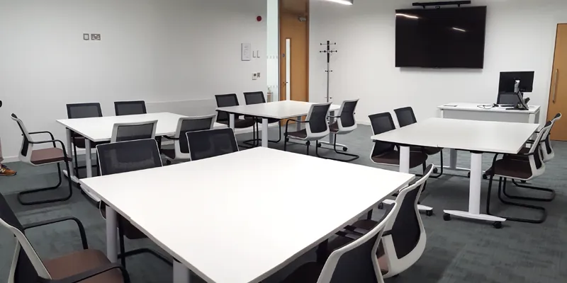 A lecture room with grouped tables and chairs A lecture room with grouped tables and chairs