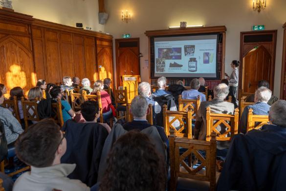 Group of people sitting watching professor present lecture on screen