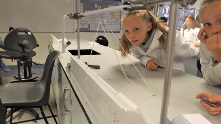 Student staring in amazement at paperclip floating in air using string and magnets