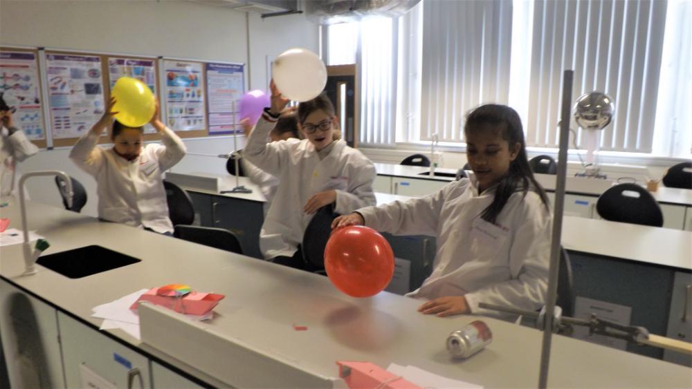 Three young girls rubbing balloons off their heads