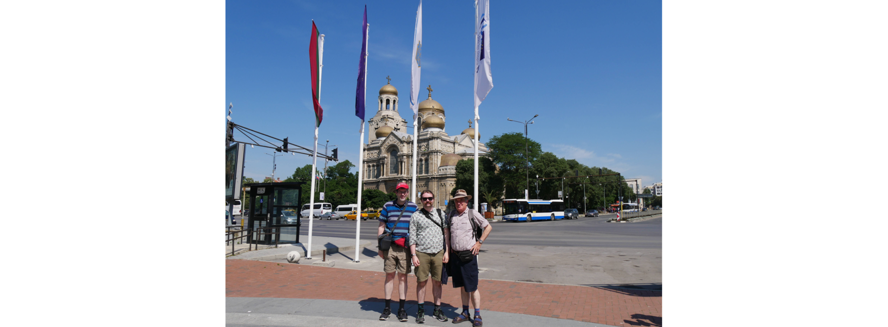 Three men standing in front of three flagpoles 