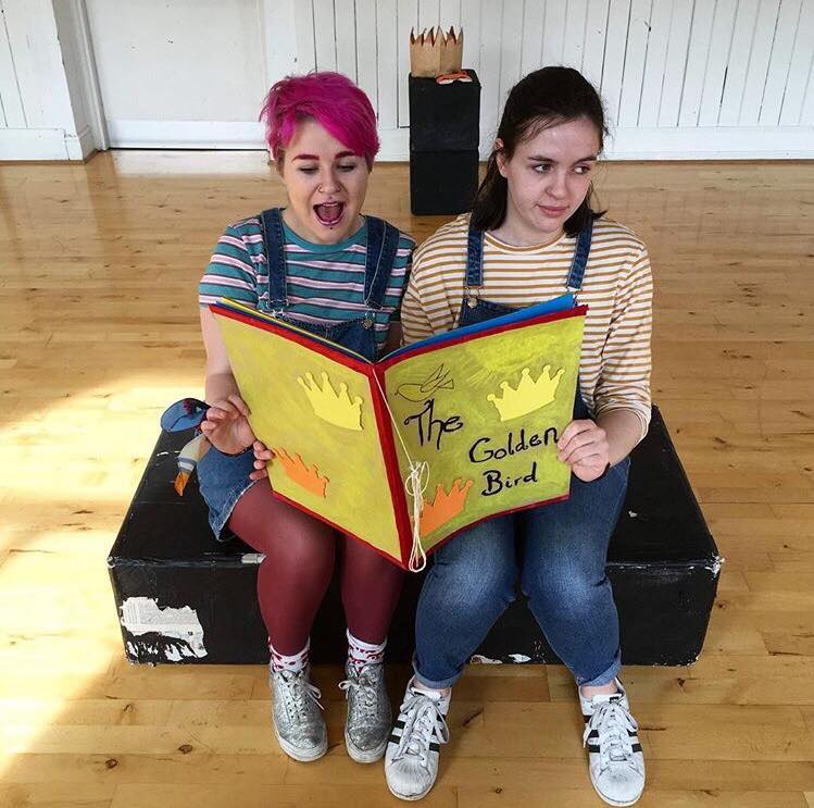 Two FYP students sitting and reading as book as part of rehearsals 