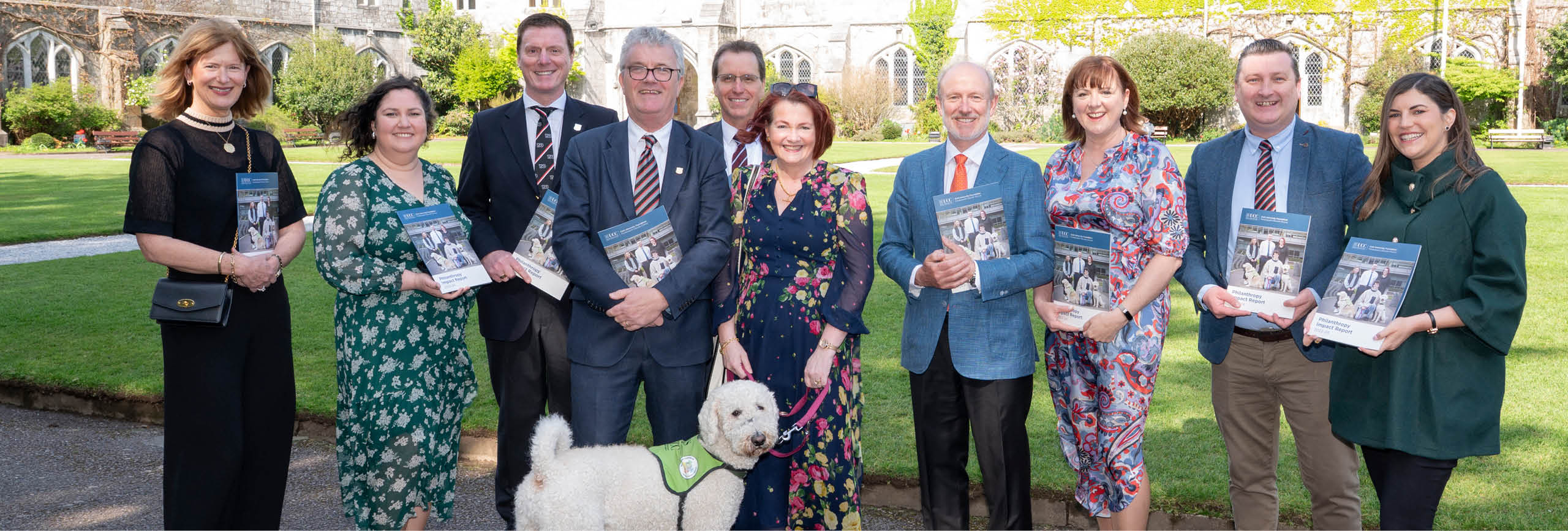 Advancement office staff pose on the quad with one of the ucc support dogs and copies of the new impact report