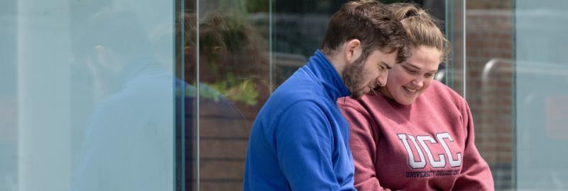 Two students working on a laptop outside