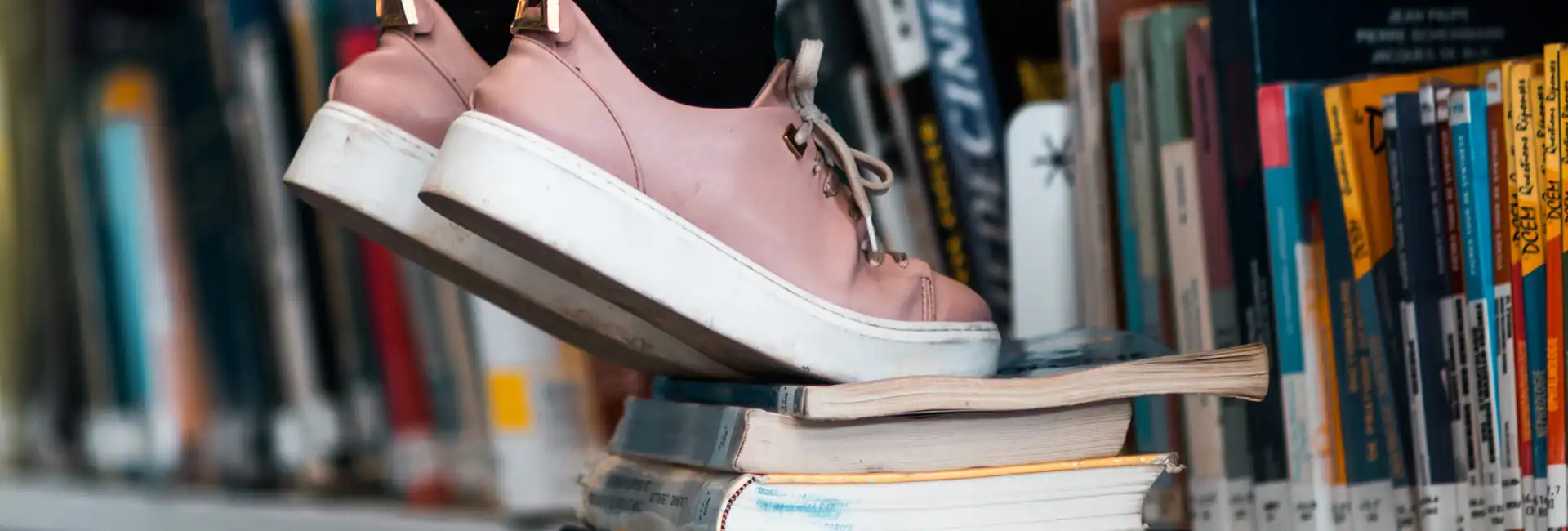 Pink shod feet stand on a stack of books