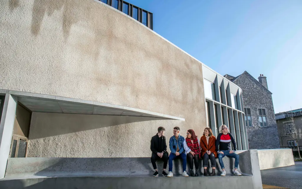 Students sit beneath the Student Hub Building