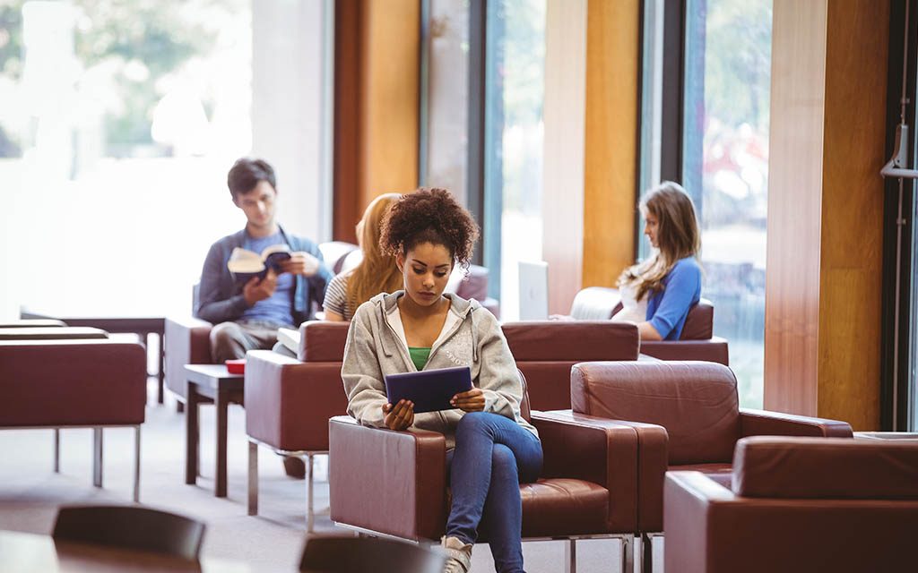 A female student sitting down looking at an ipad