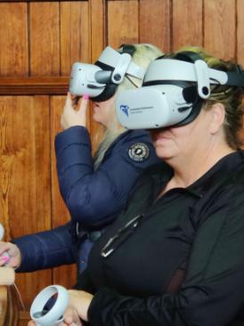 Two women try on virtual reality headsets in a courtroom