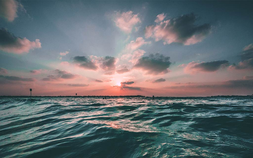 Sunset through clouds over ocean