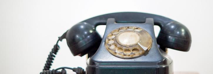 A black rotary telephone on a white background
