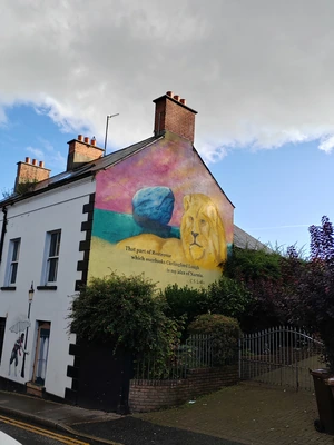 A colourful mural on the side of a house against a blue sky with white clouds A colourful mural on the side of a house against a blue sky with white clouds