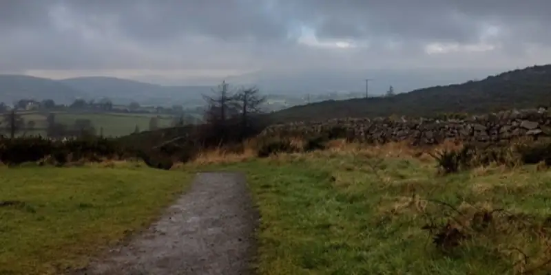 A stone road through a boggy landscape with dark grey clouds overhead A stone road through a boggy landscape with dark grey clouds overhead