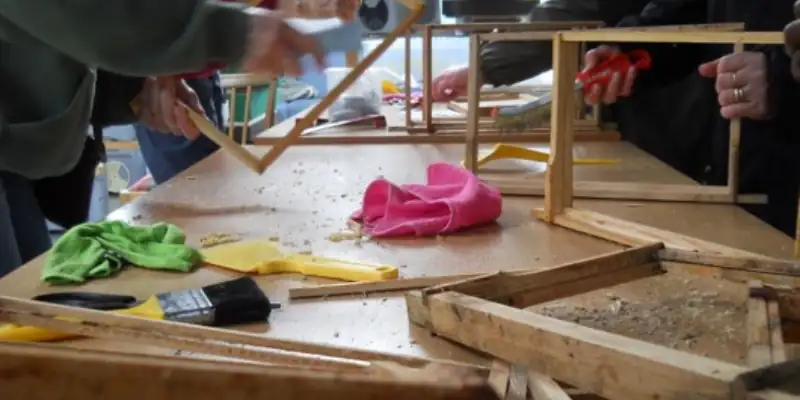 A table strewn with tools, wood and sawdust as people make brood frames for bee hives A table strewn with tools, wood and sawdust as people make brood frames for bee hives