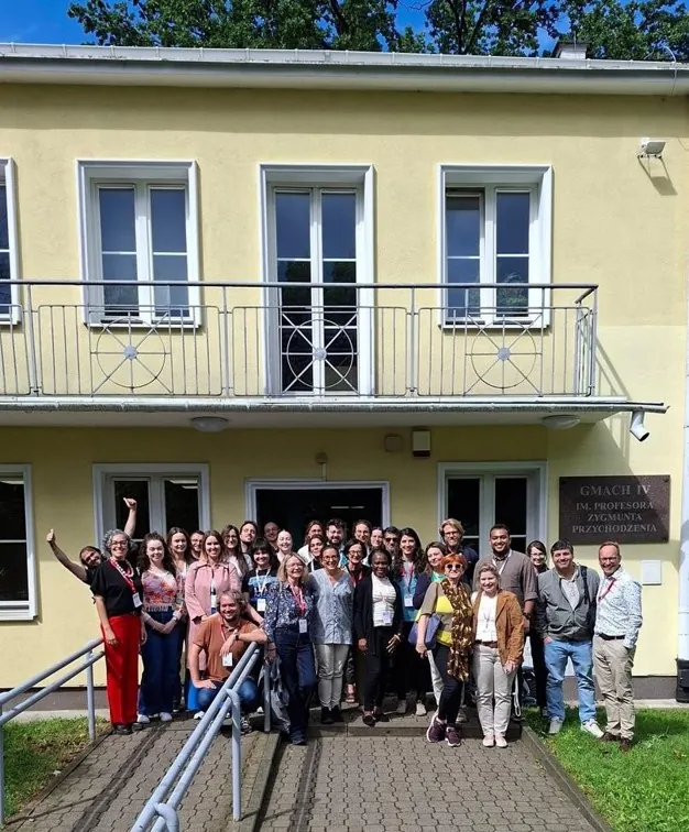 A group of people smile at the camera in front of a yellow building. A group of people smile at the camera in front of a yellow building.