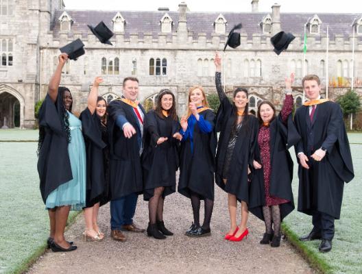 Postgraduate certificate students throwing hats in quad