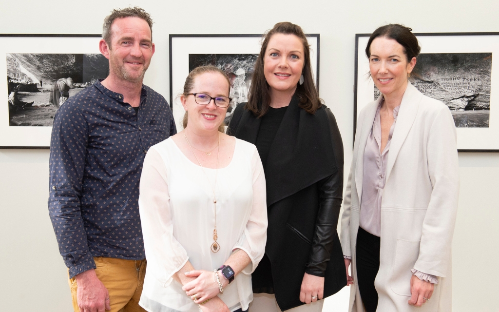 Four people standing for a photograph, smiling