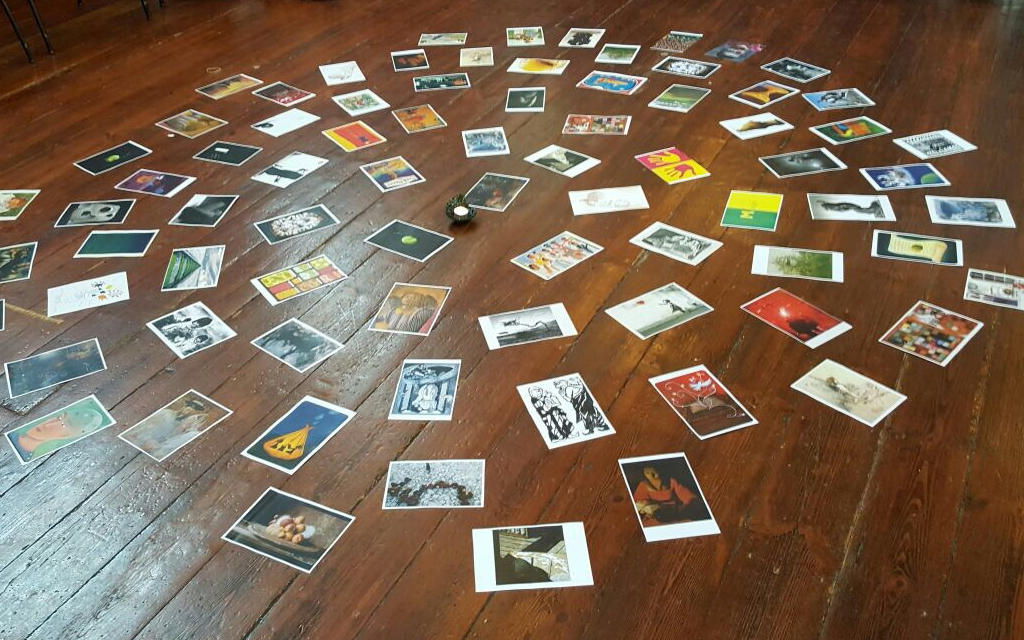 candle on a wooden floor with lots of coloured images placed around it, radiating from it in circles