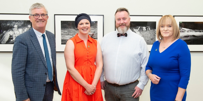 Group of 4 people standing together, smiling