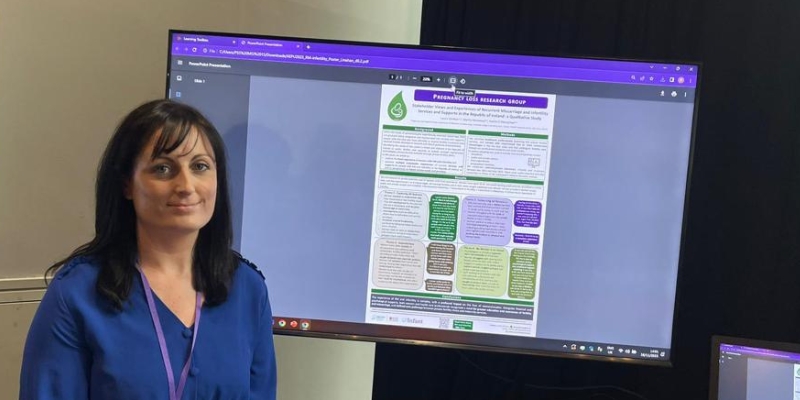 Woman standing beside a screen with an electronic poster on display