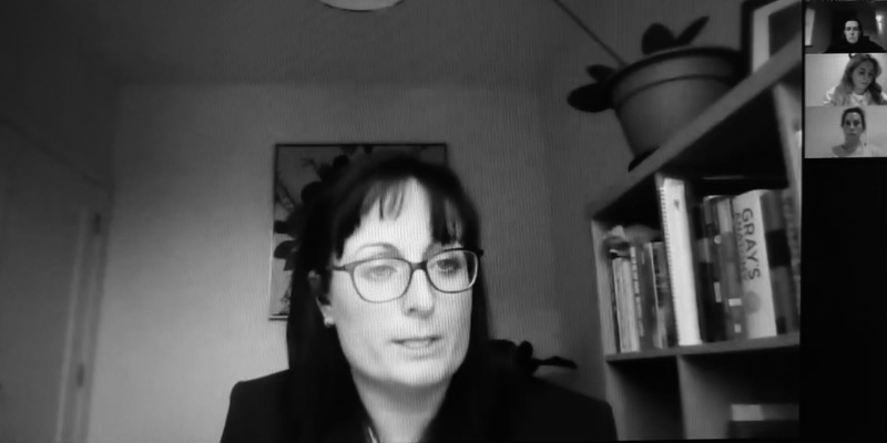 black and white close-up photo of woman presenting at a virtual meeting