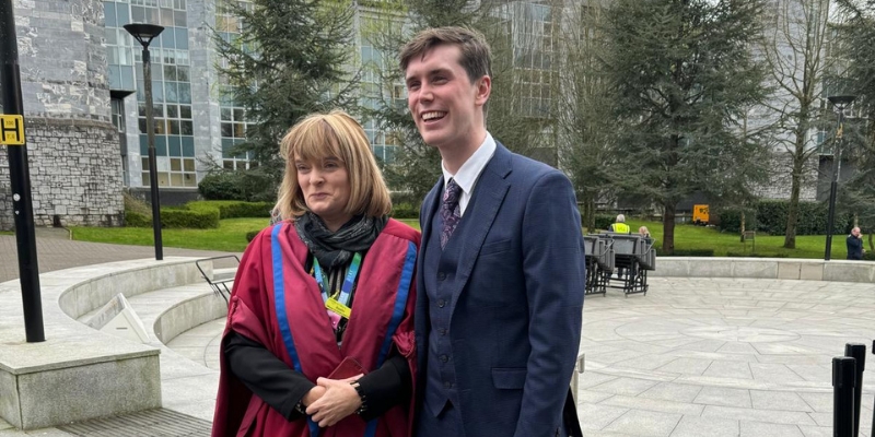 Woman and man standing for a photograph on graduation day