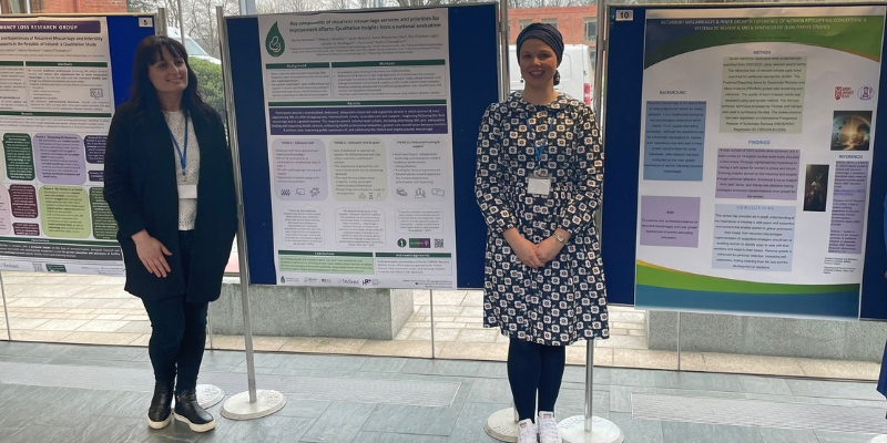 Two women standing between three large poster boards