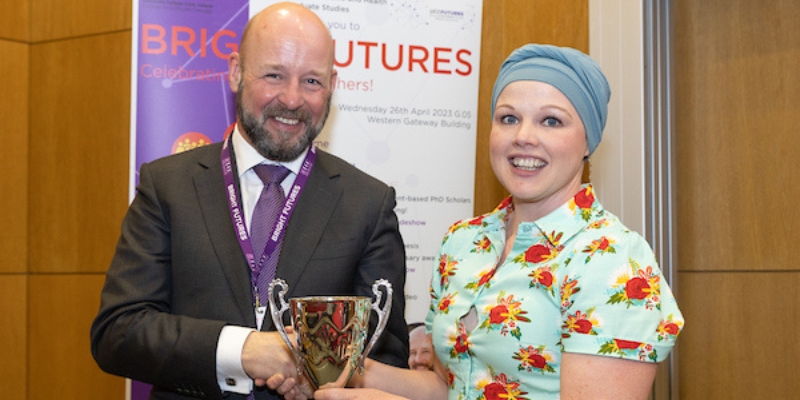 man handing silver trophy to a woman, shaking her hand