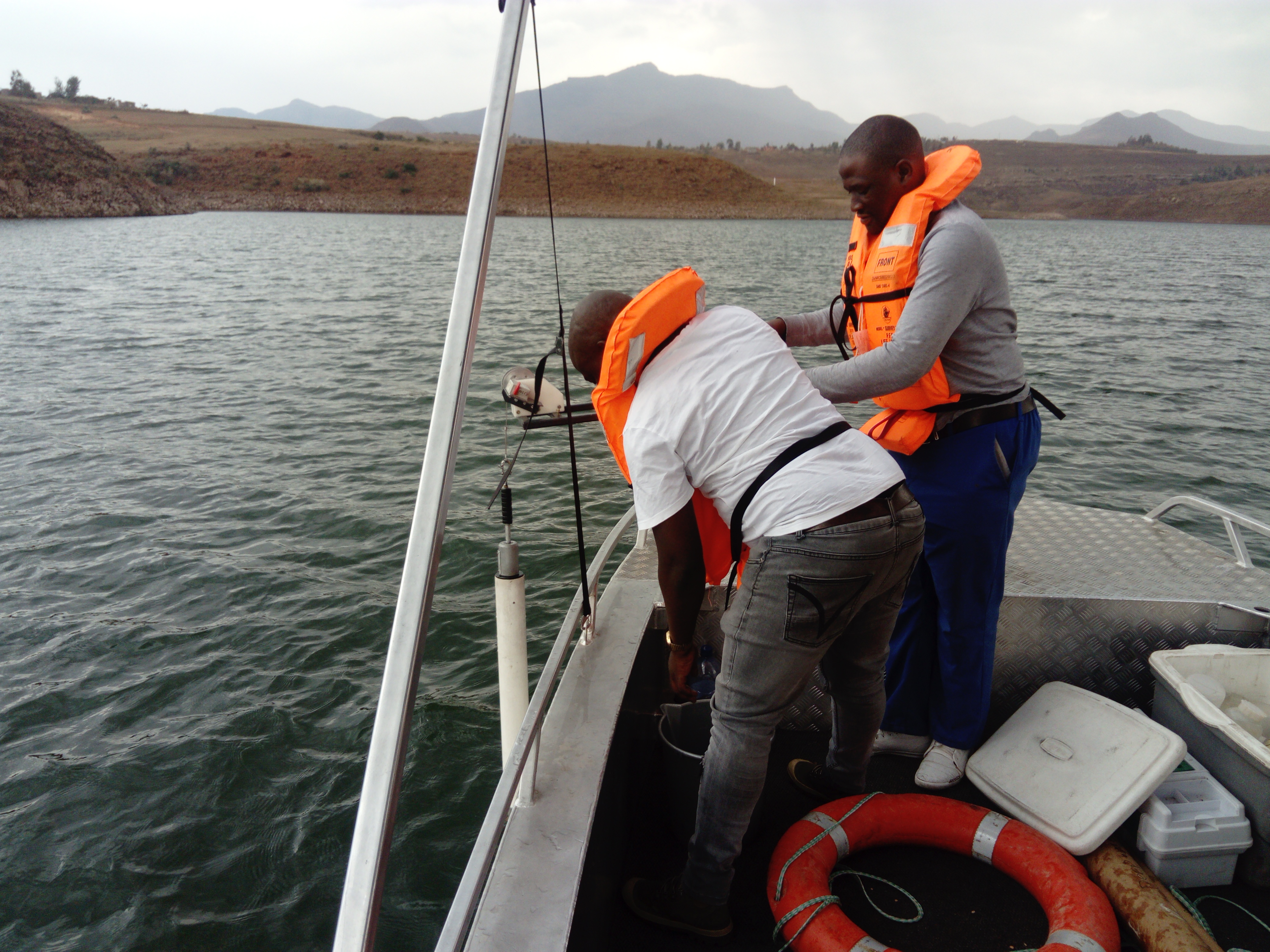 Ntiea and a colleague collecting samples from a boat. For large waterbodies such as lakes and reservoirs, small craft such as this are necessary to collect samples from different points in the water column and from the lake bed.