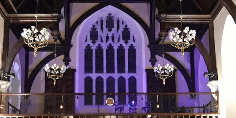 An atmospheric purple lit main window in the Aula Maxima during UCC Players' Murder On the Nile production