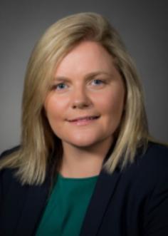 Headshot of woman with fair hair and dark jacket smiling for the camera.