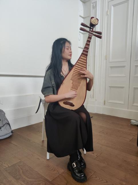 A student sitting and playing the pipa instrument