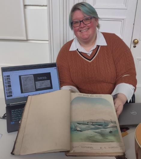 A smiling student sitting with a laptop and open book