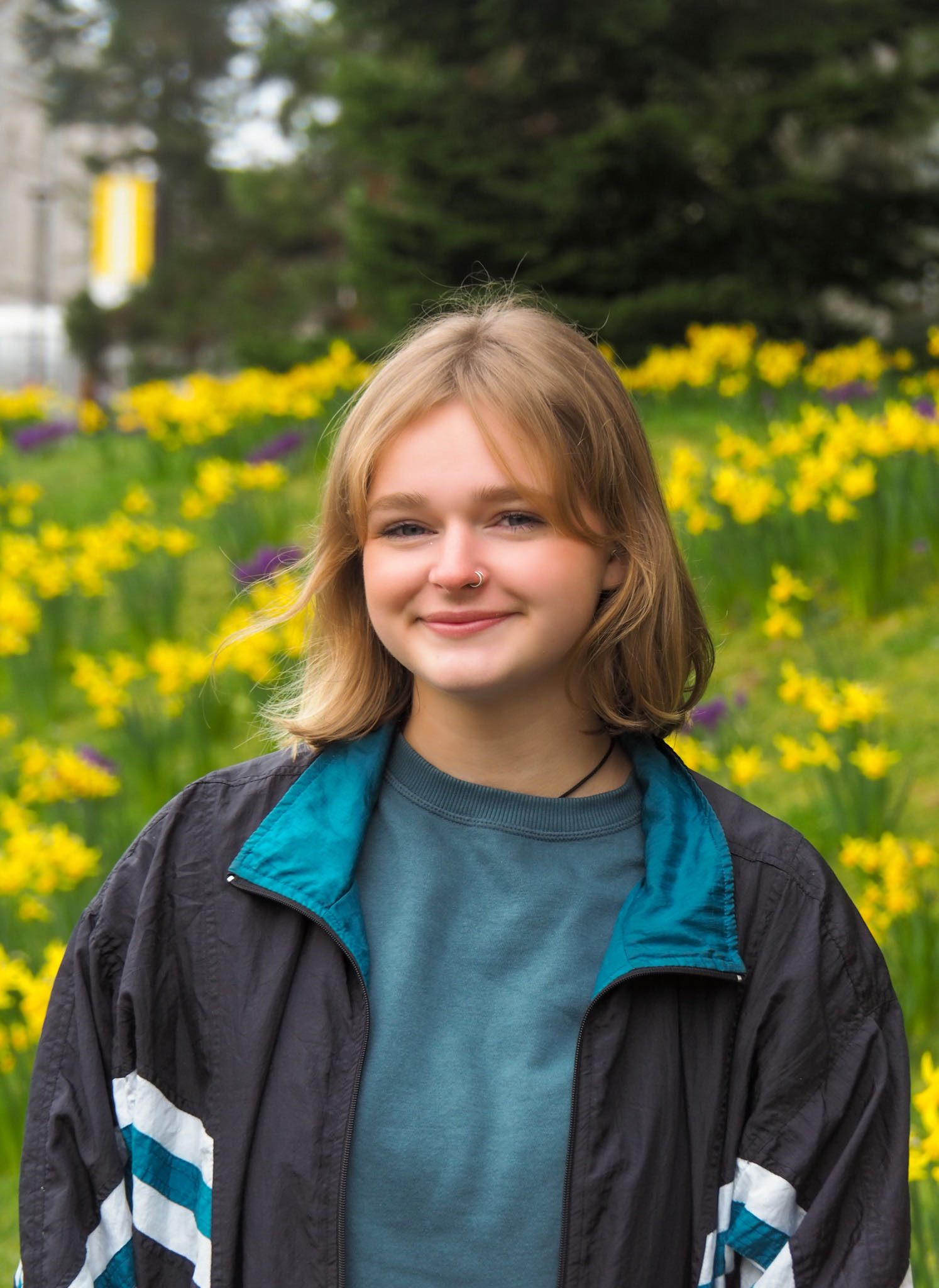 Head and shoulder shot of smiling student against a garden with yellow daffodils.