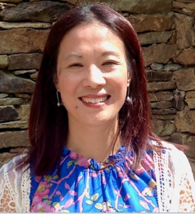 A smiling woman with shoulder length brown hair and pale skin