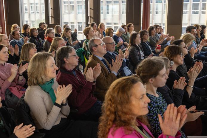 An audience sitting, clapping