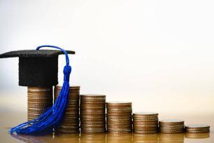 Piles of coins lined up with a graduation hat on top of one pile